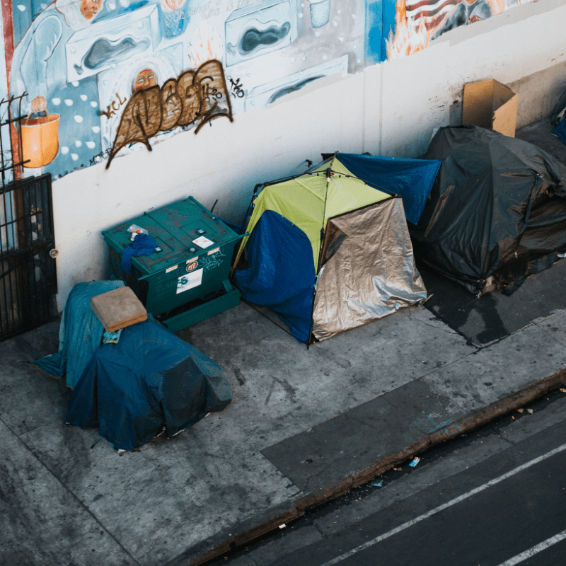 Several tents against a graffiti wall alongside an urban street
